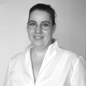 Portraitfoto von Astrid Benedik mit Brille in einer Bluse in schwarz weiß